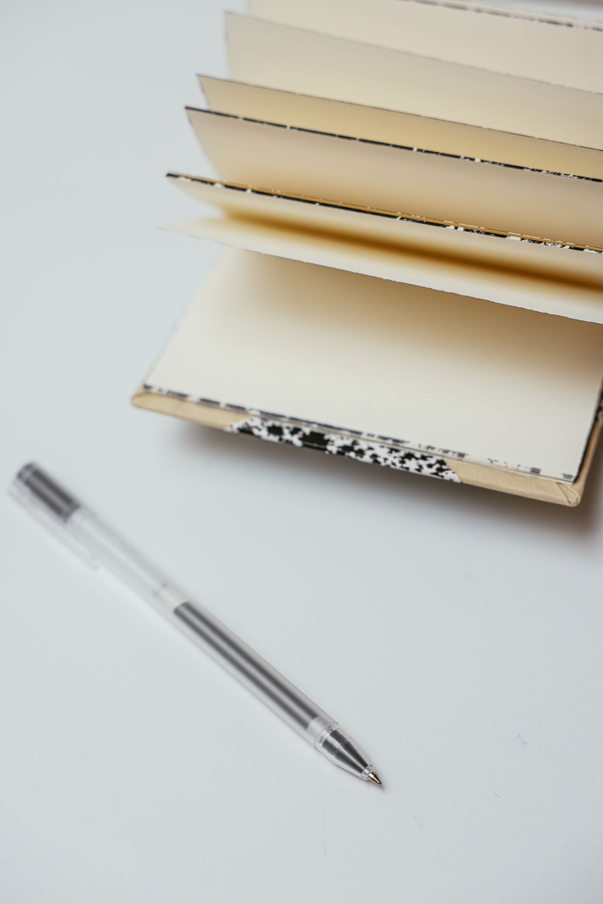 Minimalist setup of an open notebook and pen on a white surface, perfect for writers.